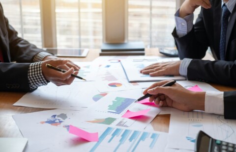 Business professionals discussing charts and data in a meeting room, reviewing financial graphs and reports on the table