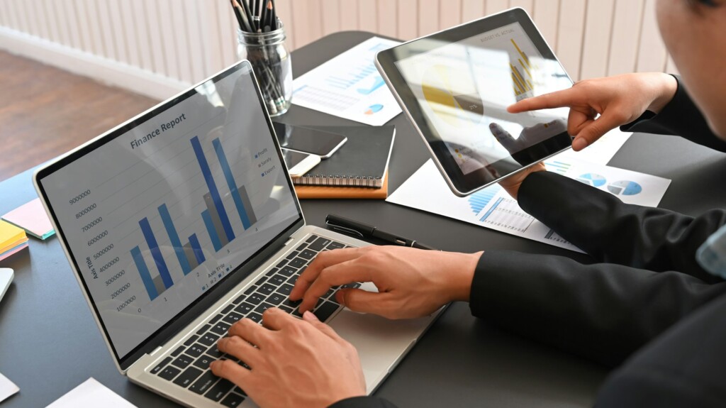 Person analyzing finance report and charts on laptop and tablet