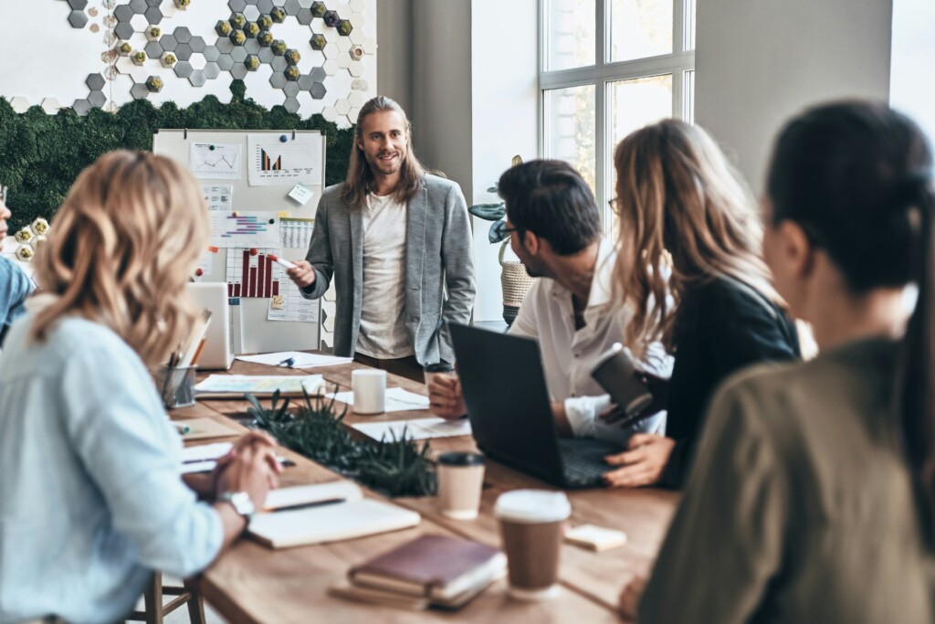 Startup team collaborating around a table in a modern, eco-friendly office with charts and greenery, representing conscious consumerism and sustainable business practices in 2025.