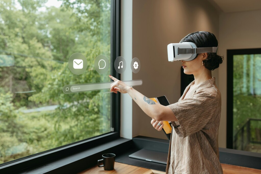 Woman wearing a virtual reality headset interacting with a transparent digital interface in a modern workspace, illustrating immersive spatial computing technology in enterprise innovation.