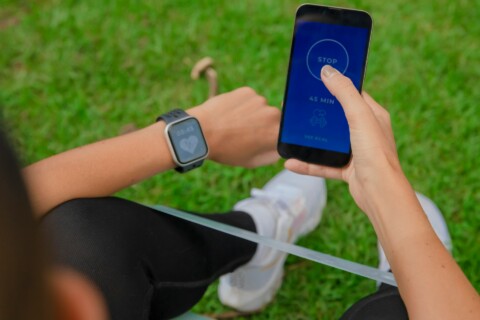 Person using a fitness smartwatch and mobile health app to track real-time heart rate and exercise data outdoors, illustrating AI-powered preventive healthcare technology.